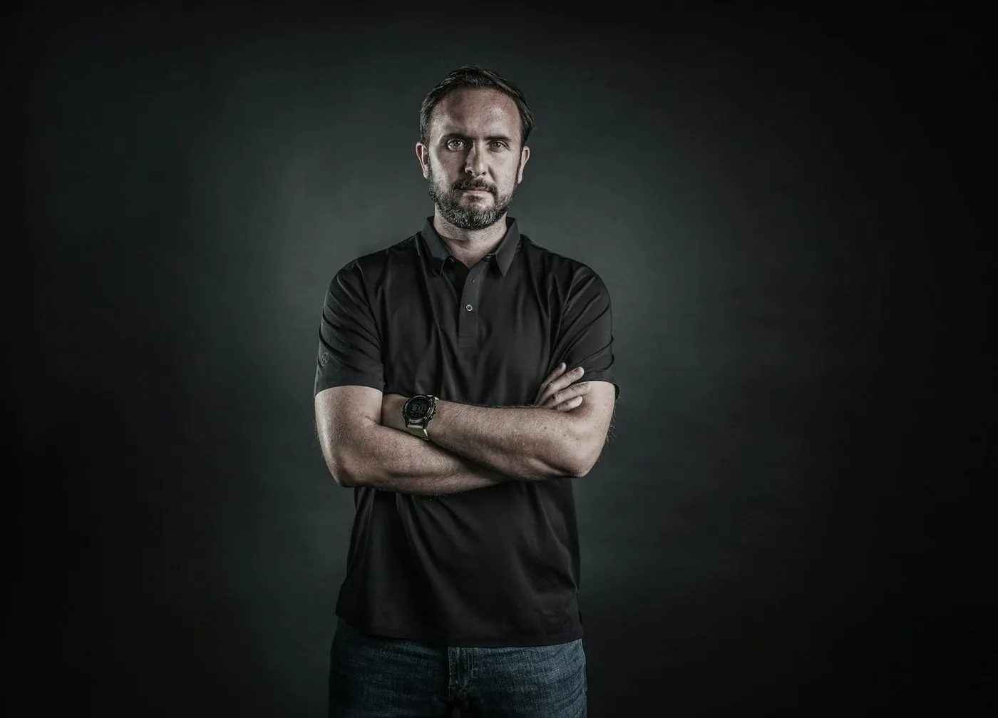 A fit man in his forties with arms crossed, studio light